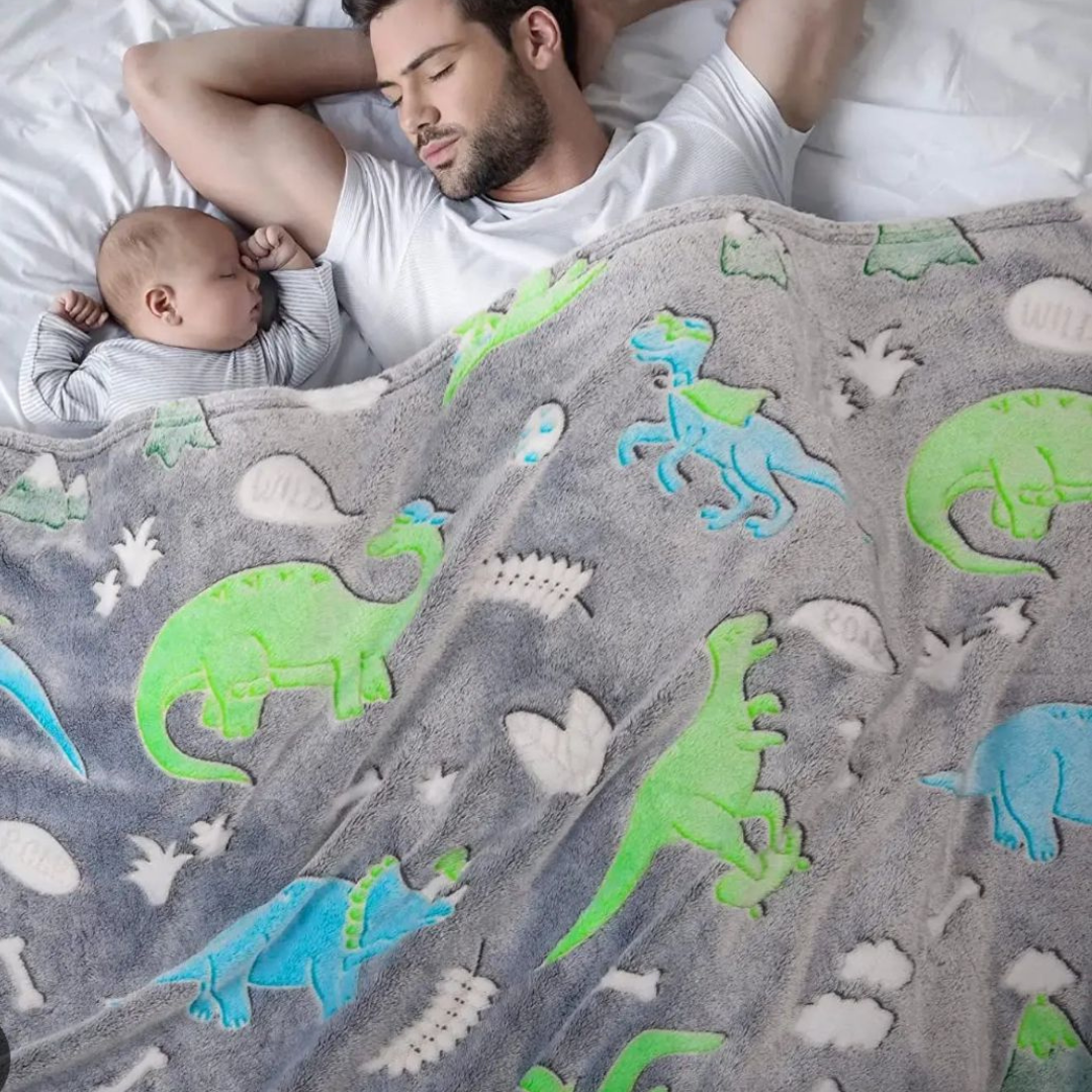 Otac i sin pokriveni svetlećim ćebetom sa motivima dinosaurusa